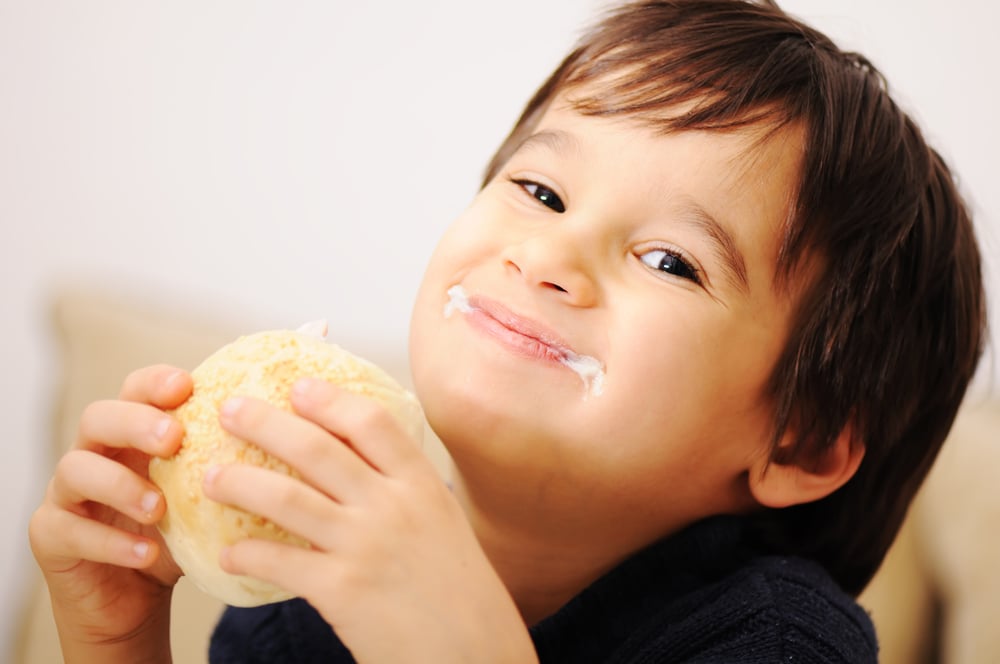 Boy eating healthy sandwich on white background